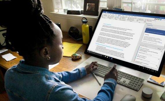 Young person using a wireless keyboard to work on a document in Microsoft Word on a large desktop monitor