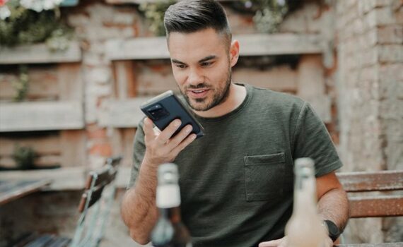 man in gray crew neck long sleeve shirt holding black smartphone