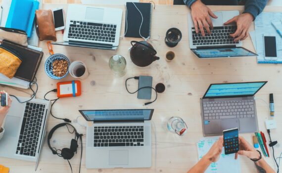 people sitting down near table with assorted laptop computers