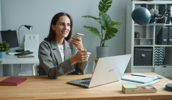 lady holding phone while working on a laptop